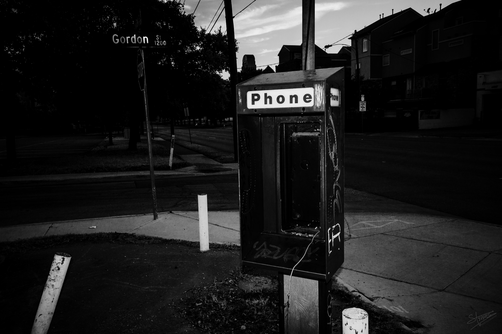 Payphone shell with its payphone ripped out, leaving only a frayed wire.