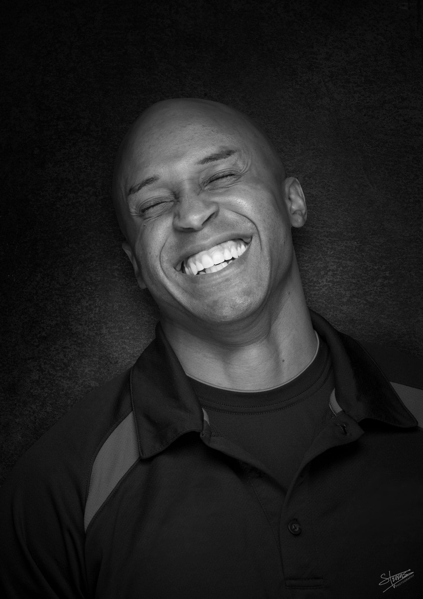 J.J. Johnson, eyes closed, head tilted back slightly, smiling broadly.