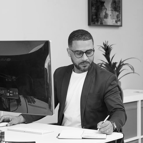 Man at computer jotting notes in a journal