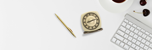 Old egg timer set to 15 minutes next to keyboard, pen, coffee, and cherries.